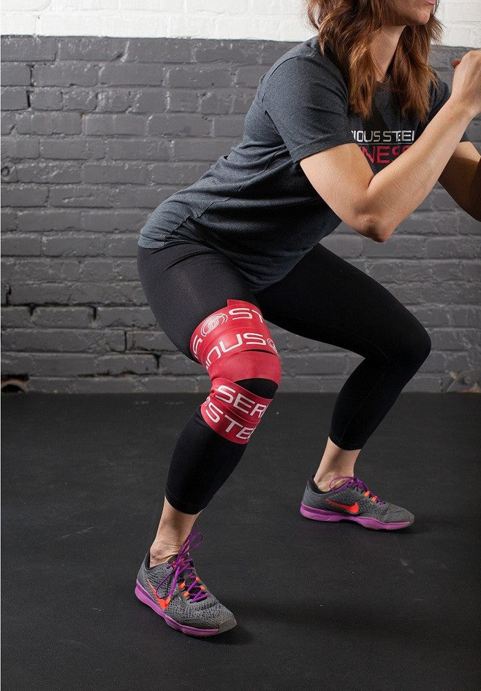 A woman using a compression band on her thigh after a workout.